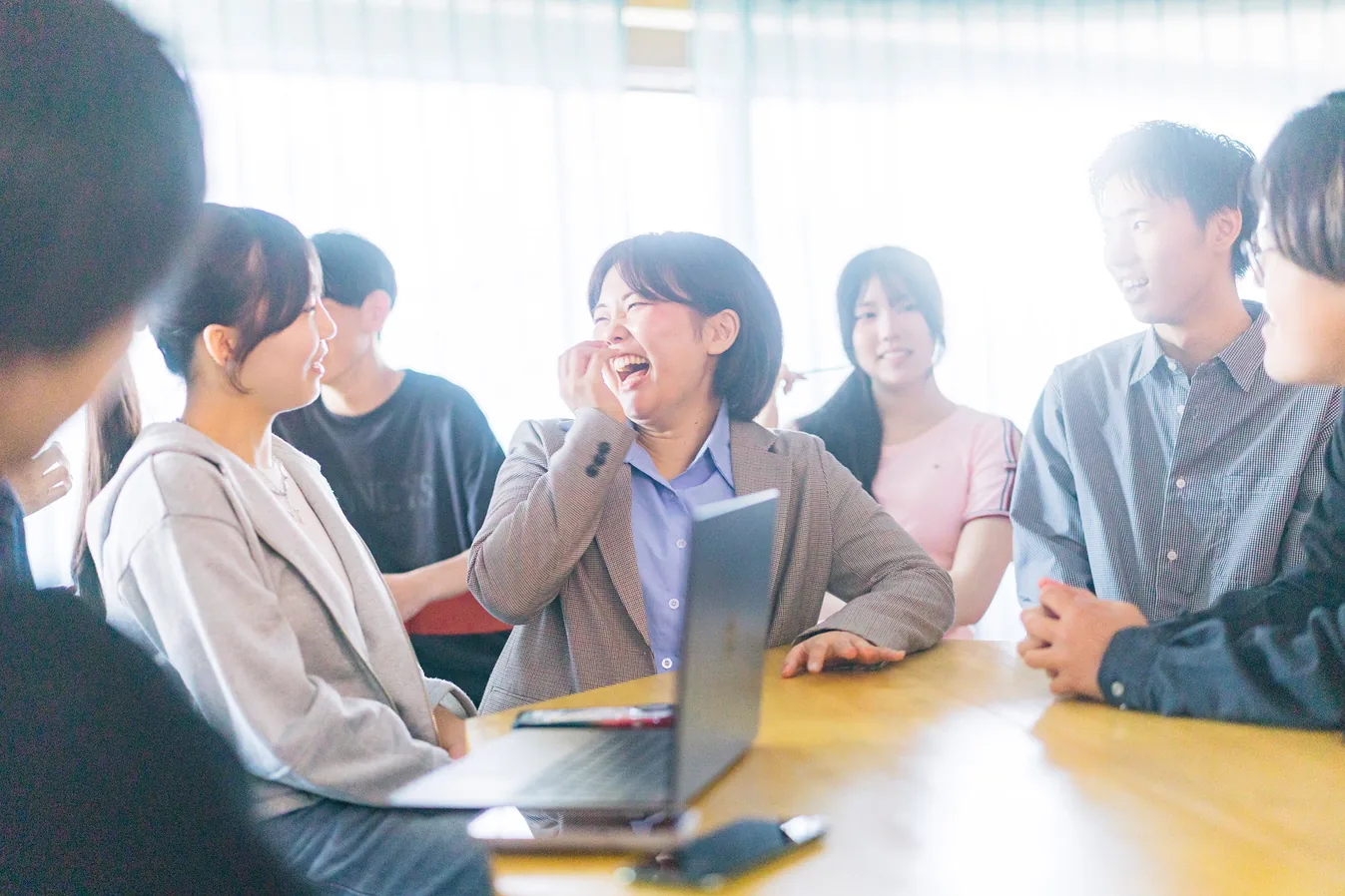 テーブルを囲んで笑い合いながら話す生徒たち